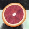 A still life of a ruby red grapefruit cut in half
